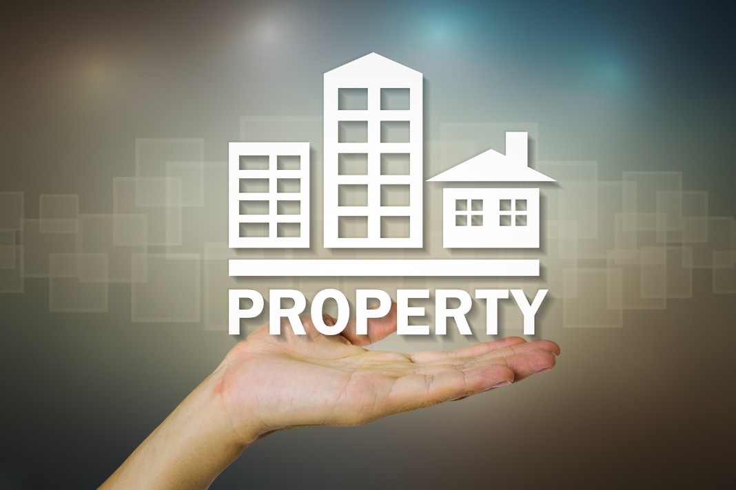 Open hand holding property icon with buildings, representing ActivePropertyCare.com About asset care and home maintenance.