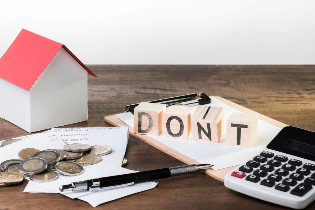 Model house, repair bills, coins and calculator showing property care mistakes that can lead to higher maintenance costs.