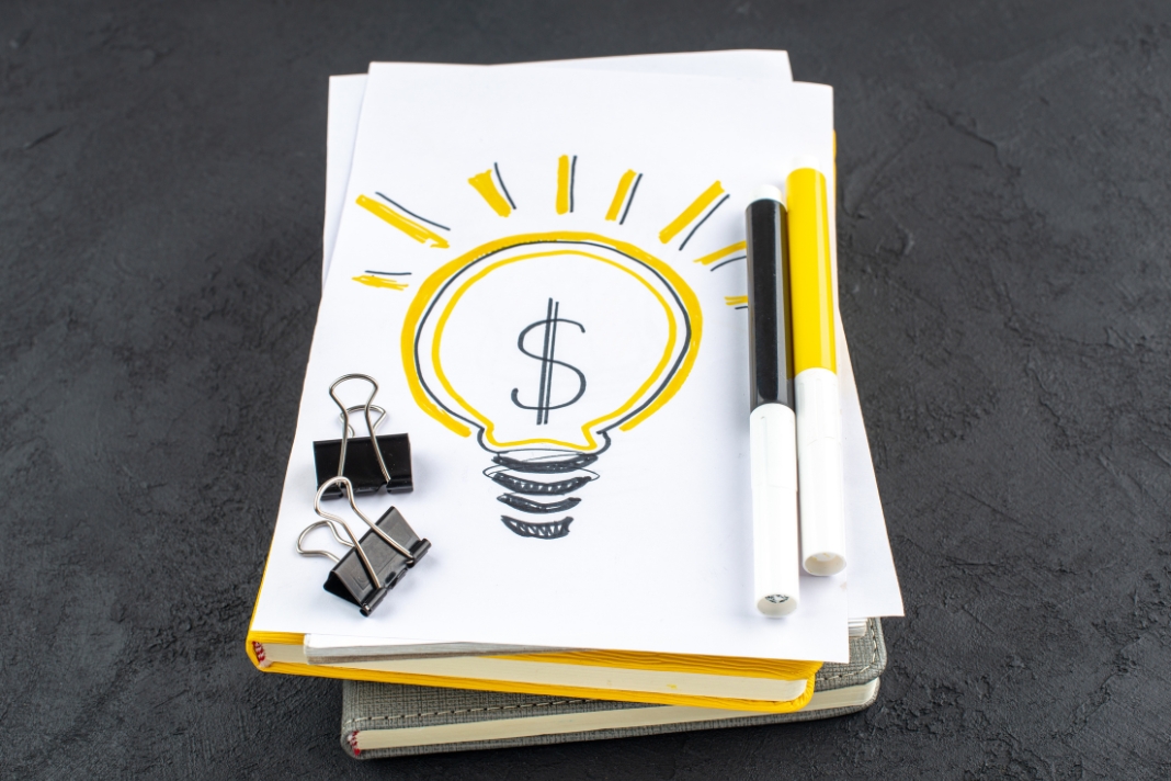 How To Guides ActivePropertyCare image showing a lightbulb money sketch, markers, and notebooks for property cost planning.
