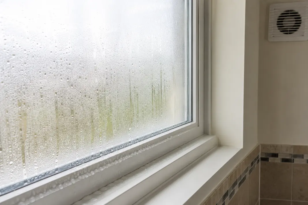 Bathroom condensation forming on a cold window near an extractor vent