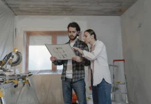 Home Renovation Budget: Estimate Costs, Set Contingency, and Control Changes Homeowners reviewing a home renovation budget and floor plan inside a remodeling project.