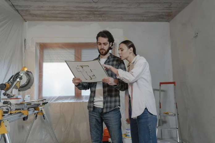 Homeowners reviewing a home renovation budget and floor plan inside a remodeling project.
