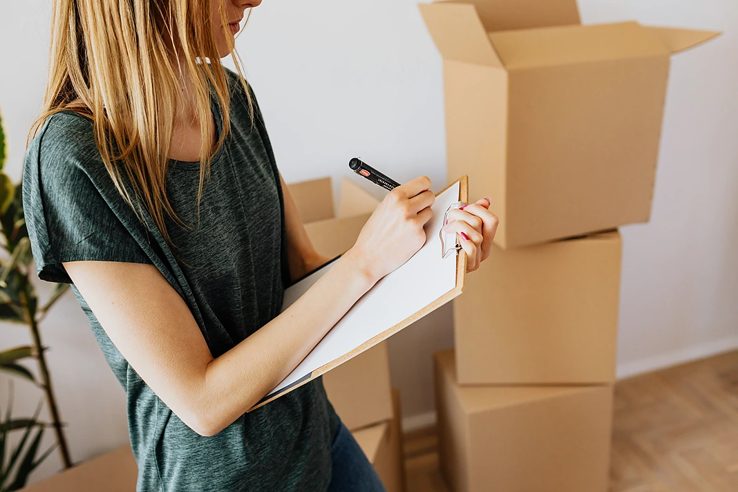 Tenant recording property condition beside moving boxes during move-in
