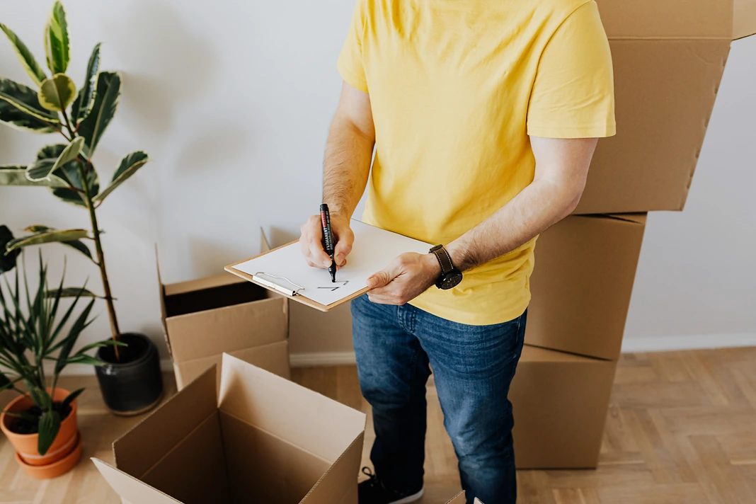 Tenant completing a move-out condition checklist beside packed boxes